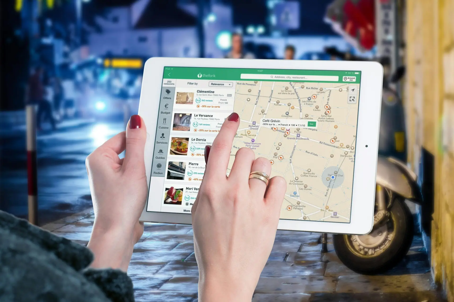 Services Hands using a digital map on a tablet in an urban setting at night, illustrating navigation and technology.