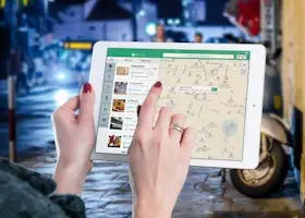 Home Hands using a digital map on a tablet in an urban setting at night, illustrating navigation and technology.