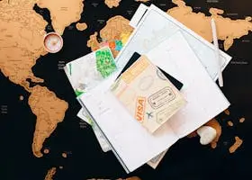 Home A flat lay of travel planning items on a map, featuring a compass, notebook, and guide for wanderlust enthusiasts.