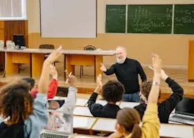 pexels photo 8199166 8199166 Professor engaging with students in a lively university classroom discussion as students raise hands.